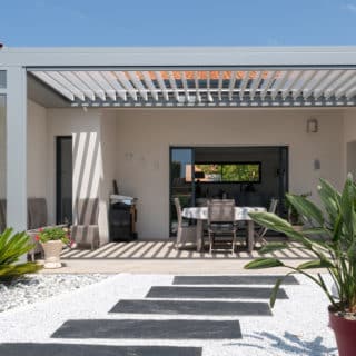 Façade d'une maison neuve de 139 m² à Saint-Sulpice-de-Royan, mettant en valeur son design moderne avec enduit blanc.
