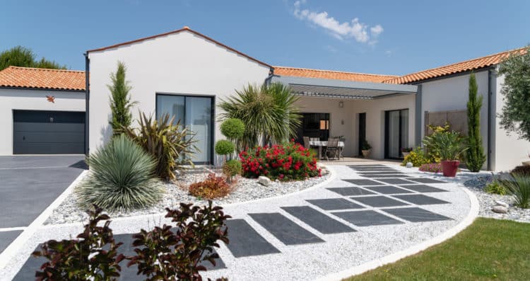 Extérieur d'une maison neuve de 139 m² à Saint-Sulpice-de-Royan, avec un enduit blanc et des menuiseries gris anthracite.