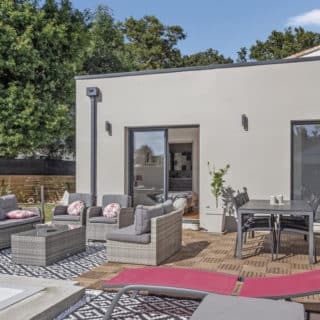 Vue sur la façade arrière d'une maison moderne en Vendée avec jardin aménagé et piscine, idéale pour la vie en famille.