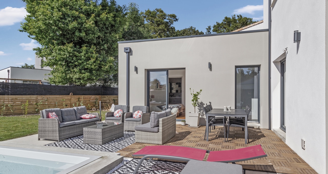 Vue sur la façade arrière d'une maison moderne en Vendée avec jardin aménagé et piscine, idéale pour la vie en famille.