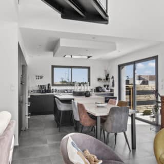 Grande pièce de vie lumineuse d'une maison contemporaine située à La Roche-sur-Yon, avec cuisine ouverte et espace convivial.