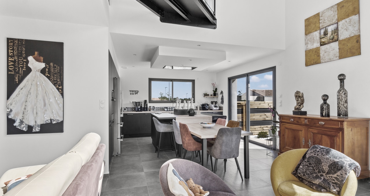 Grande pièce de vie lumineuse d'une maison contemporaine située à La Roche-sur-Yon, avec cuisine ouverte et espace convivial.