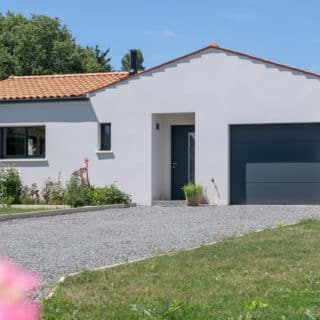 Vue extérieure d’une maison neuve à Saint-Romain-de-Benet (17), avec toiture en tuiles et architecture traditionnelle. 3 chambres et 2 salles de bain.