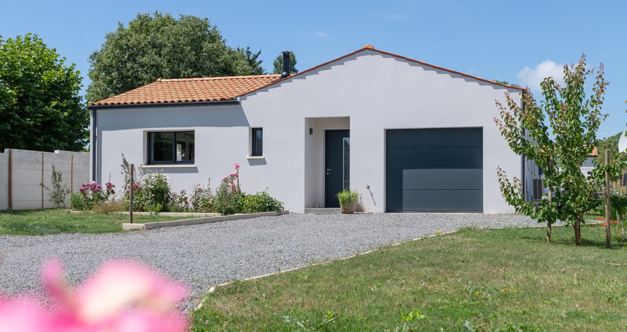 Vue extérieure d’une maison neuve à Saint-Romain-de-Benet (17), avec toiture en tuiles et architecture traditionnelle. 3 chambres et 2 salles de bain.