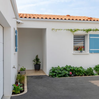 Façade avant d’une maison construite par un constructeur à Bourgneuf, Charente-Maritime, avec volets bleus en bois