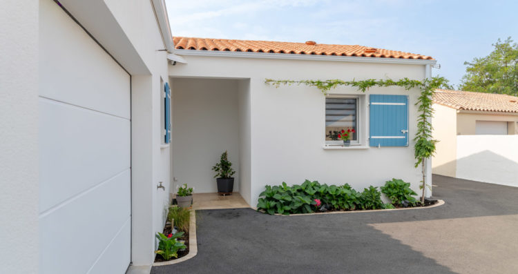 Façade avant d’une maison construite par un constructeur à Bourgneuf, Charente-Maritime, avec volets bleus en bois