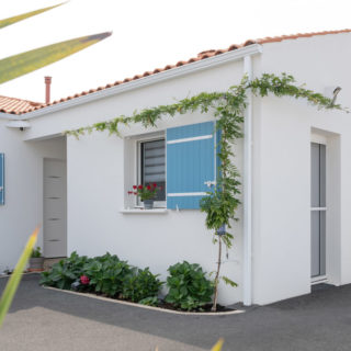 Vue avant d’une maison de constructeur à Bourgneuf, Charente-Maritime, façade blanche et volets bleus