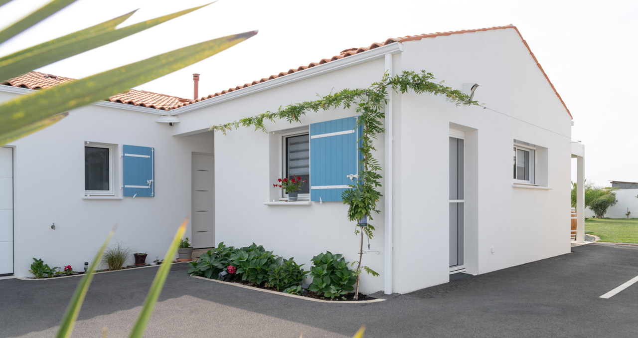 Vue avant d’une maison de constructeur à Bourgneuf, Charente-Maritime, façade blanche et volets bleus