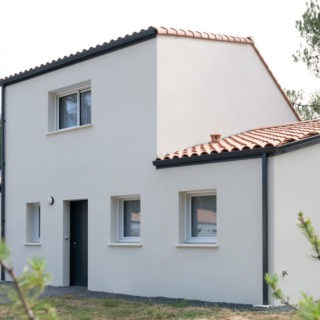 Vue supplémentaire de la façade avant d’une maison à étage à Saint-Jean-de-Monts avec enduit ton pierre et menuiseries gris anthracite