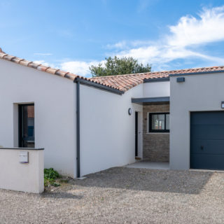 Façade avant de la maison neuve aux Sables-d’Olonne avec parement pierre et garage gris