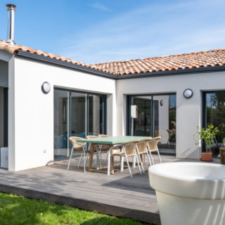 Mur de renfoncement côté jardin en enduit gris Carnac, soulignant le volume de la maison
