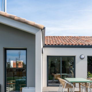 Vue côté jardin montrant la terrasse et l’ouverture sur la pièce de vie lumineuse