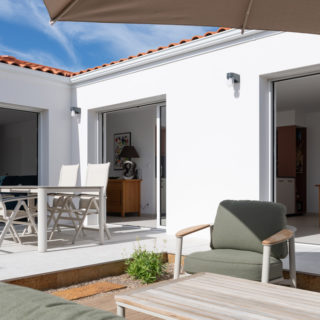 Terrasse extérieure avec vue sur jardin et piscine d’une maison neuve